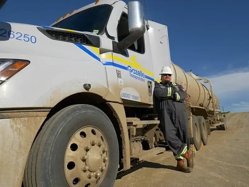 A professional CDL driver standing next to a Gazelle-branded semi tractor
