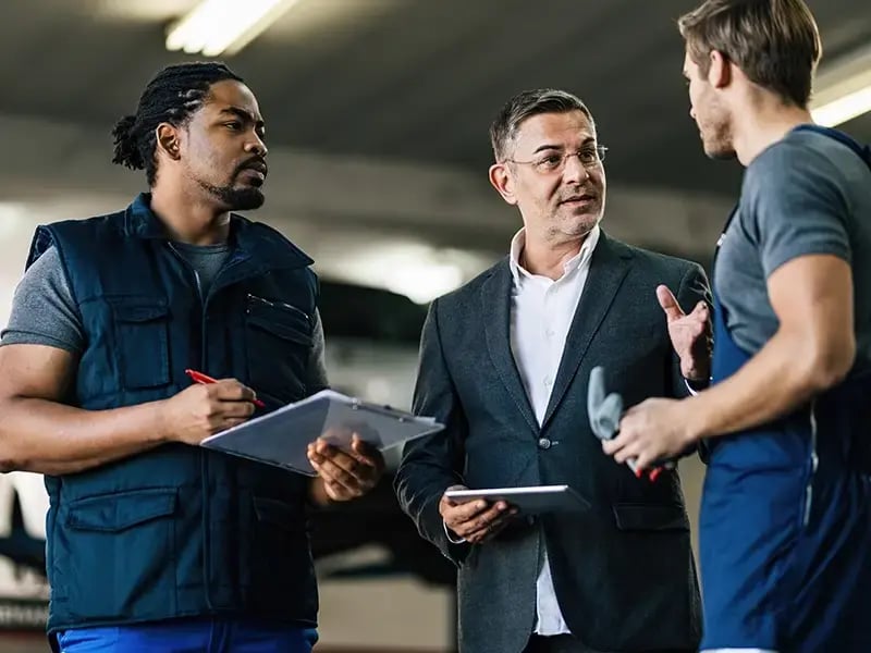 Three men at a worksite talking about safety practices.